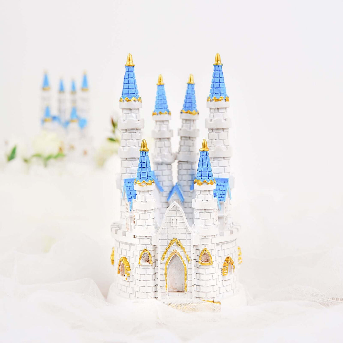 Miniature white castle model with blue rooftops and golden accents