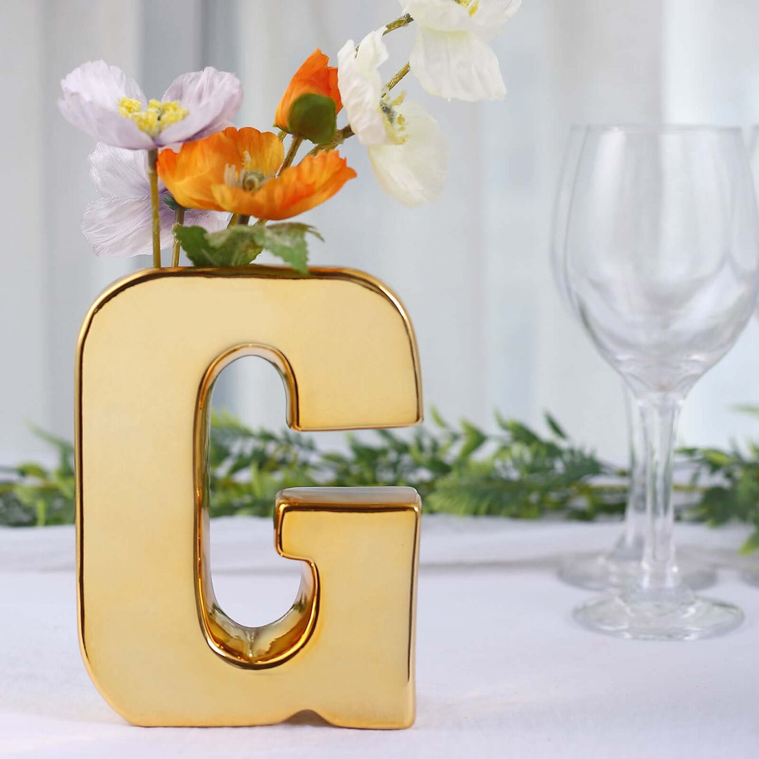 Gold letter "G" vase with flowers, elegant home decor accent.