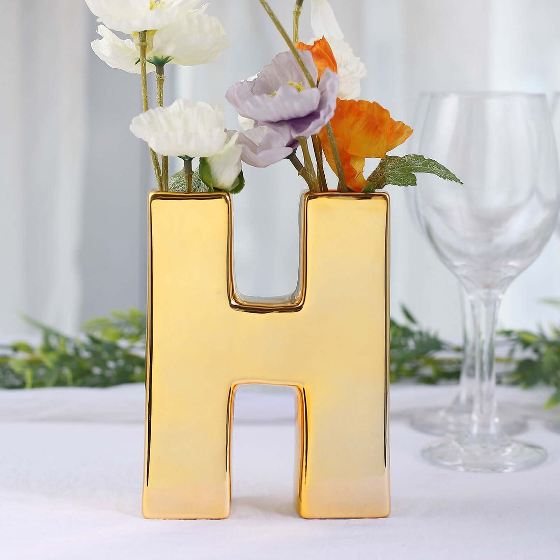 Gold letter "H" vase with flowers, perfect for home decor.
