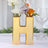 Gold letter "H" vase with flowers, perfect for home decor.