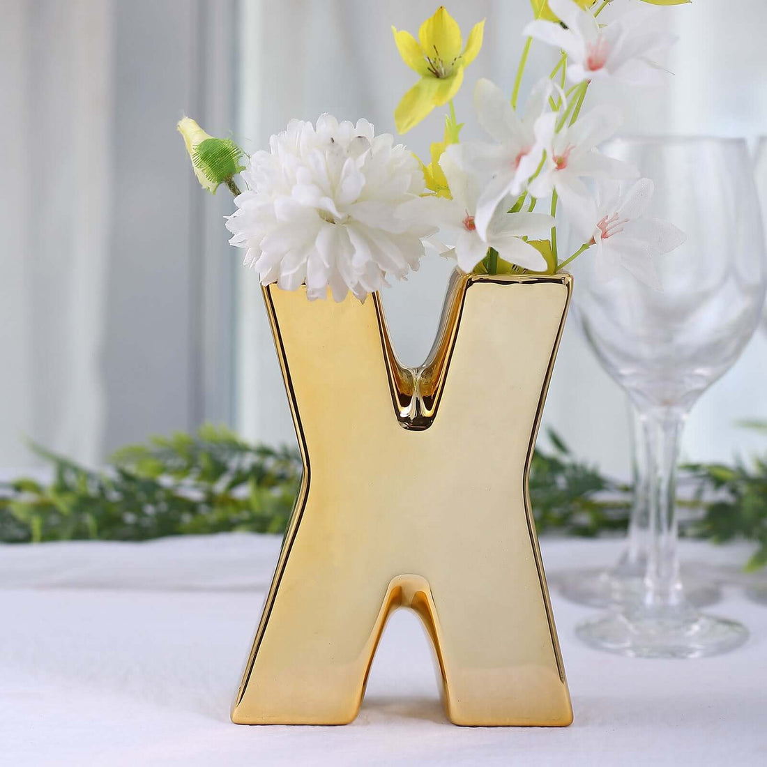 Gold "X" shaped vase with flowers, elegant decor piece for home styling.
