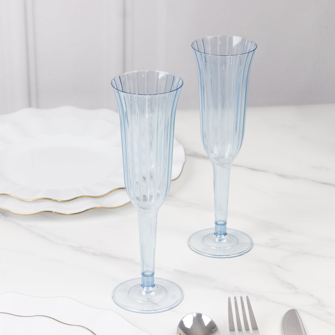 Elegant blue fluted champagne glasses on a marble table.
