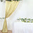 Elegant gold curtain with floral accents draped beside a white table adorned with flowers.