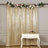 Gold sequin backdrop with floral garland and a white table with wine.