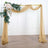 Elegant wedding arch draped with sheer fabric and floral arrangement.