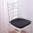 White chair with a black cushion against a light backdrop.