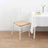 White chiavari chair with beige cushion next to a table.