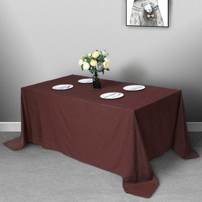 Brown tablecloth draped over a table with plates and a vase of flowers.