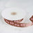 Brown ribbon with pink paw print design on a spool.