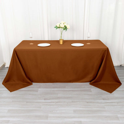 Brown tablecloth draped over a table with plates and glasses.