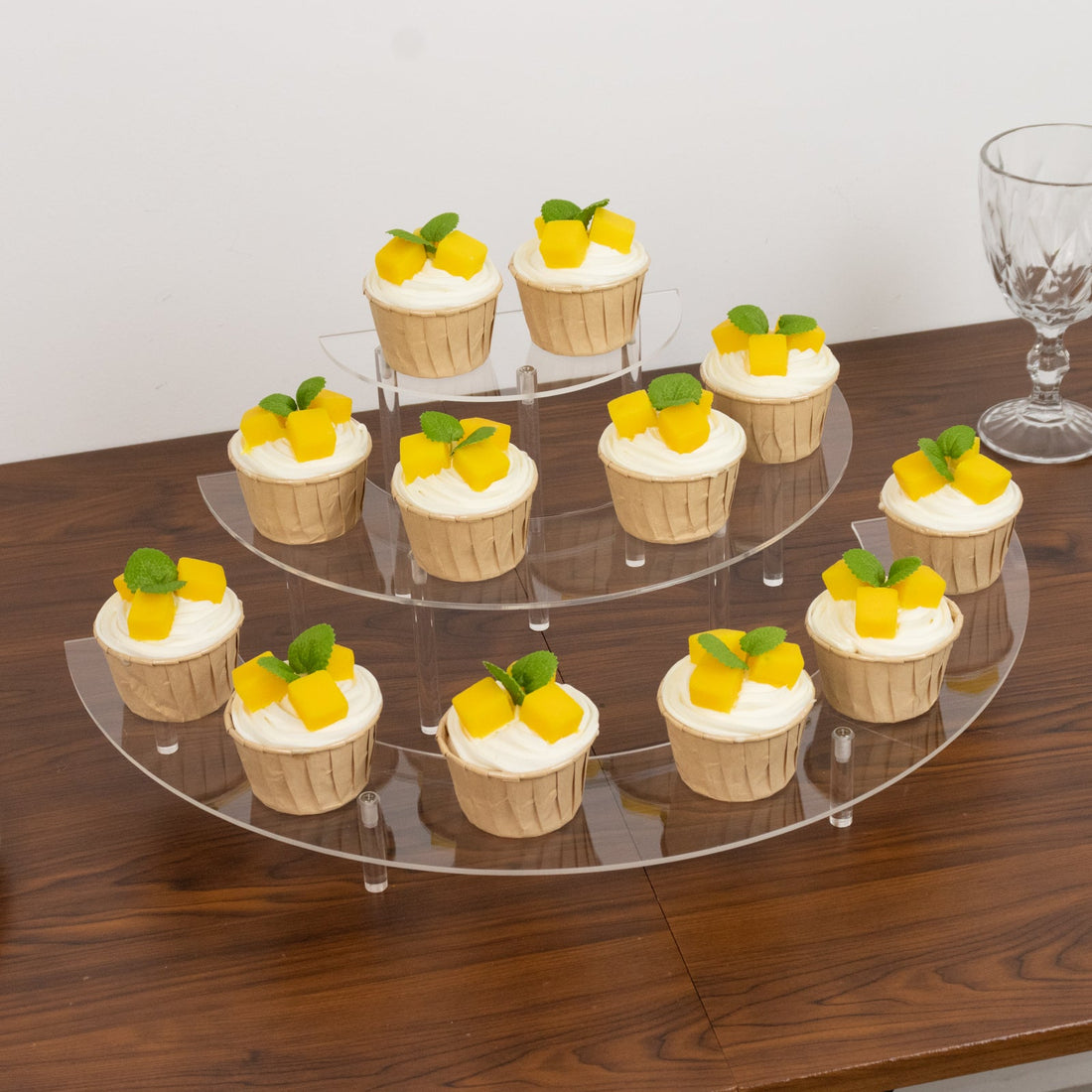 Cupcakes with mango topping displayed on a clear acrylic stand.