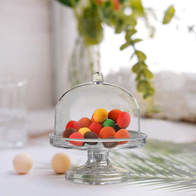 Glass cake dome with colorful candies displayed inside.