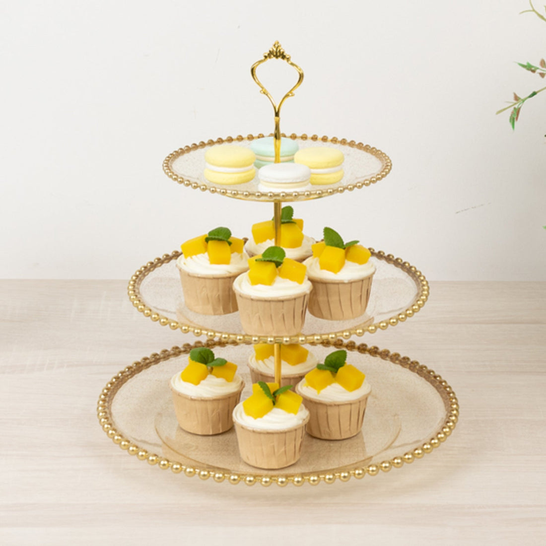Three-tiered dessert stand with cupcakes and macarons.