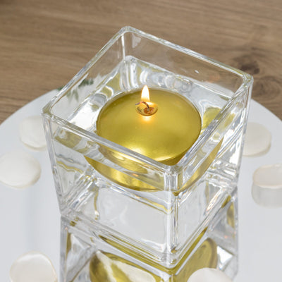Gold floating candle in a clear glass holder surrounded by flower petals.