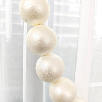 Close-up of ivory pearl-like beads on a white string against a bright background