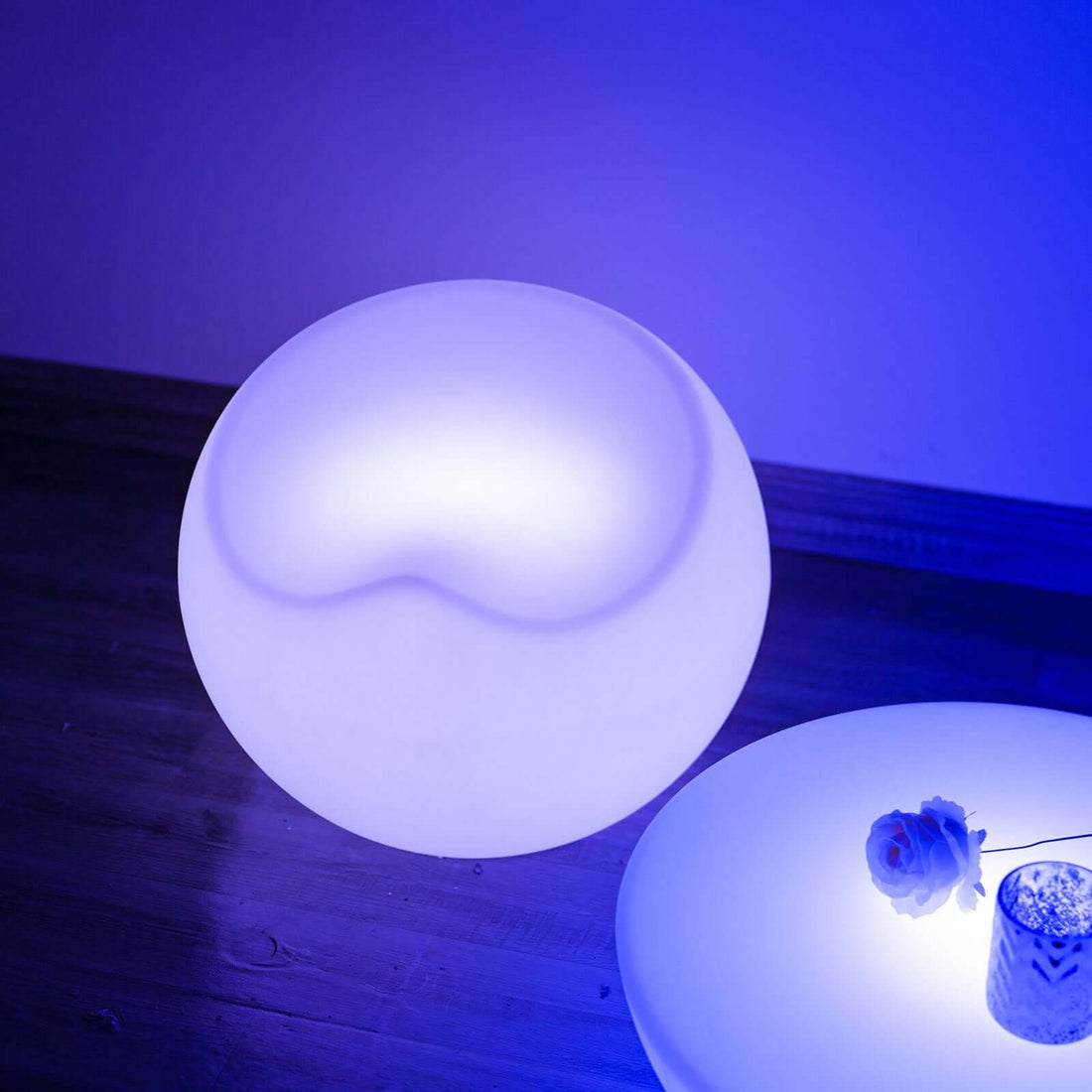 Modern round lamp with soft blue glow on wooden surface.