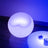 Modern round lamp with soft blue glow on wooden surface.