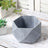 Geometric gray planter pot on wooden surface with succulents.