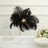 Black feather centerpiece with lights on a white pedestal, elegant table setting.