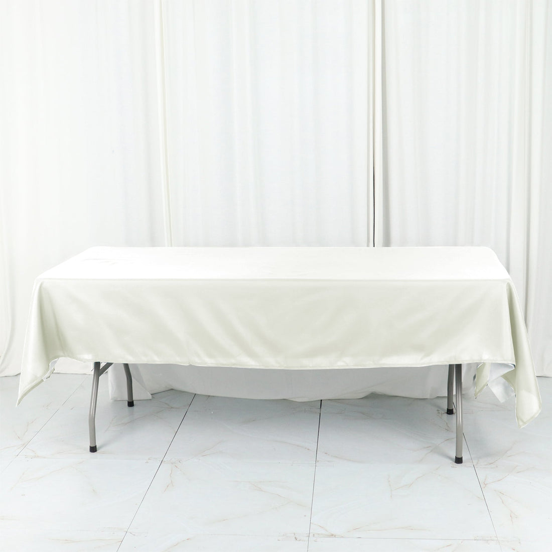 White tablecloth draped over a folding table in a studio setting.