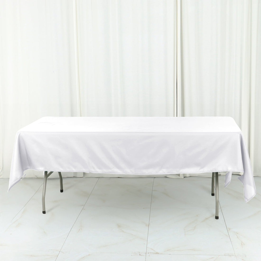 White tablecloth draped over a folding table in studio setting.