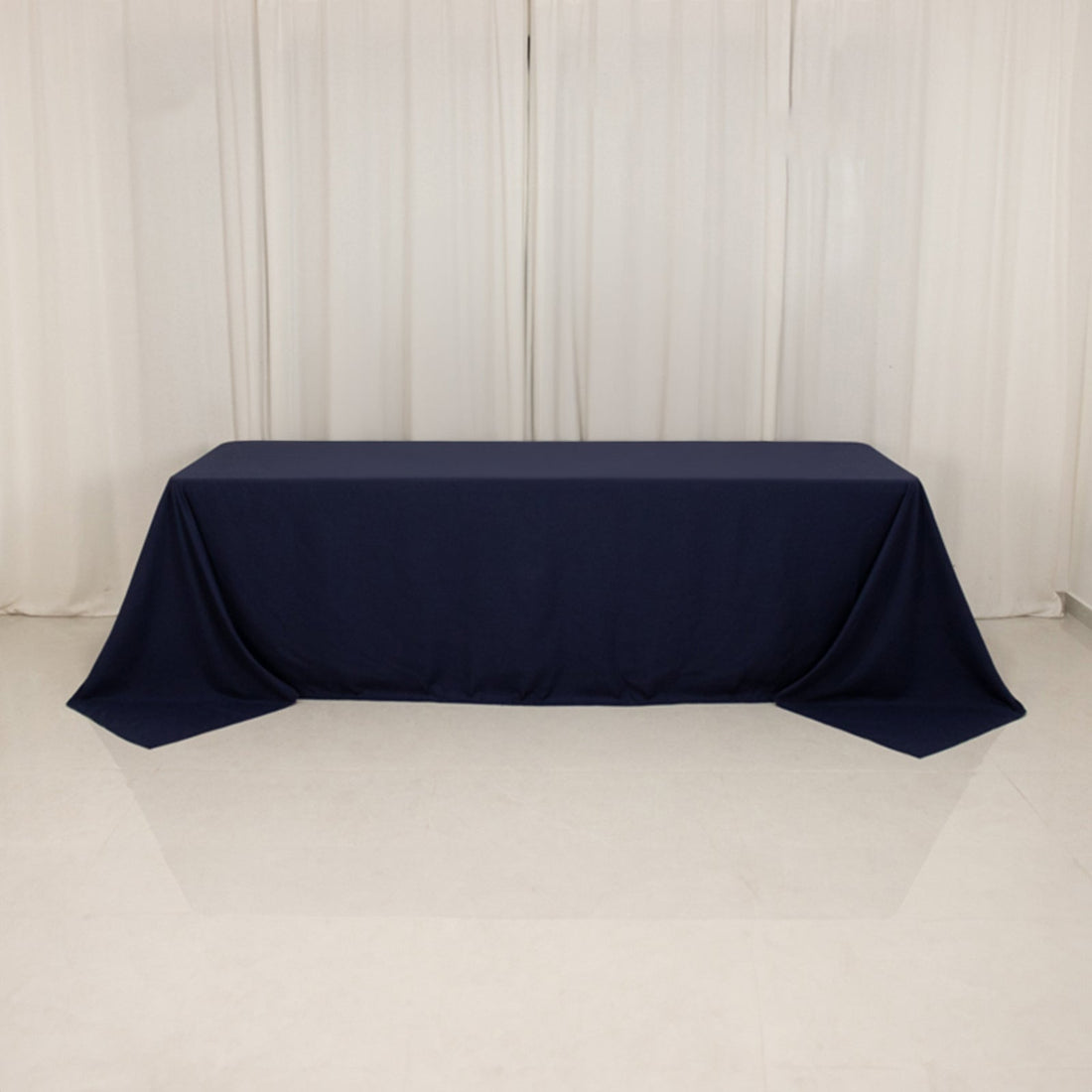 Navy tablecloth draped over a rectangular table on a white backdrop