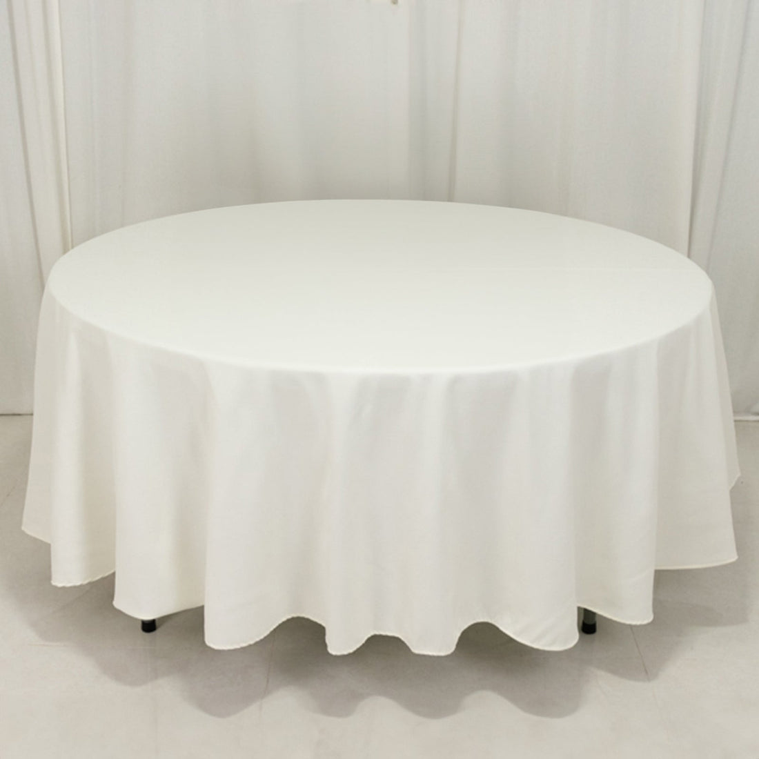 Round white table with a draped tablecloth.