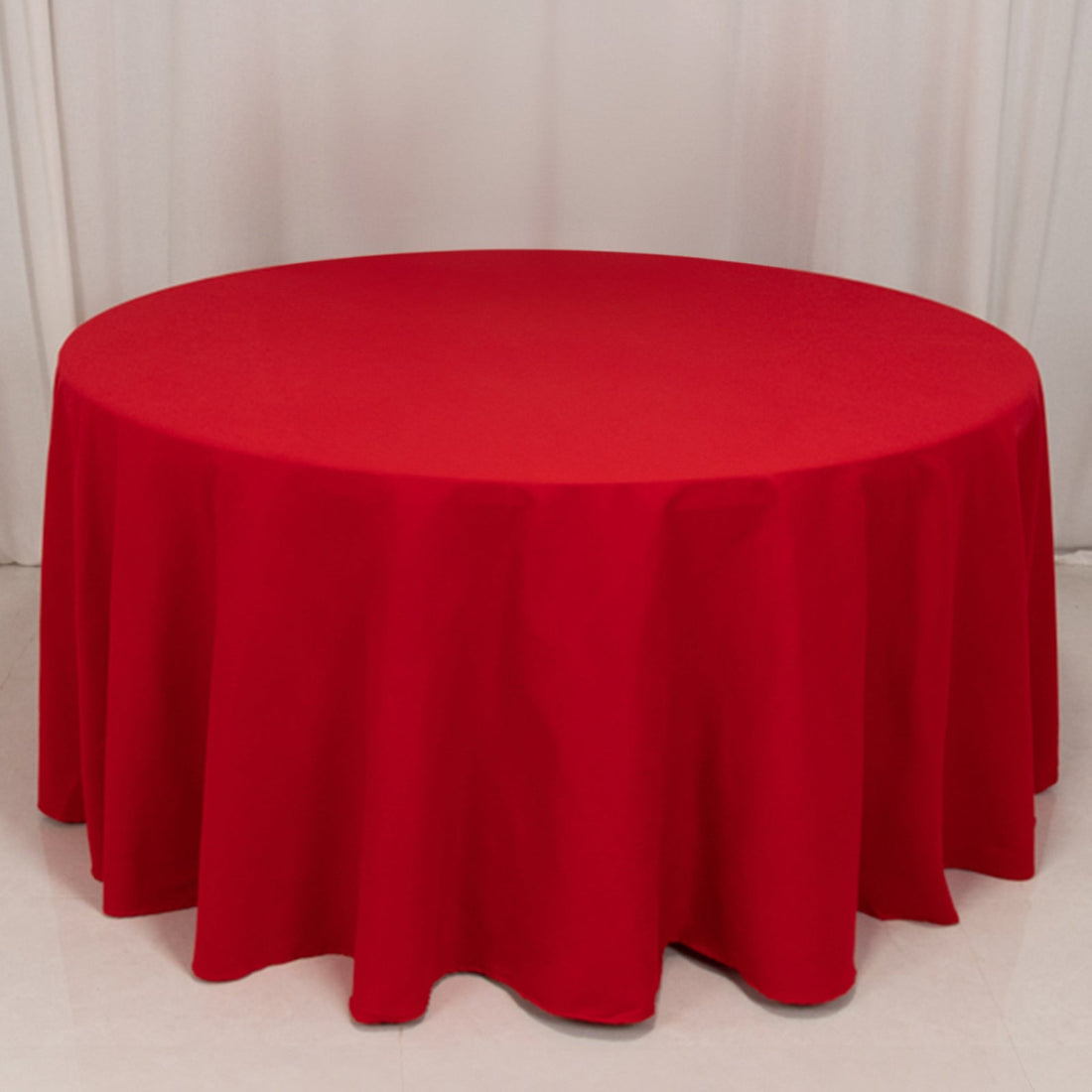 Red round tablecloth on a white surface, draping to the floor.