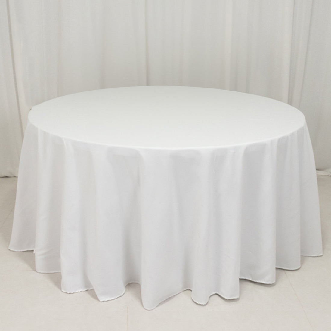 White round tablecloth draping over a circular table in a studio setting.
