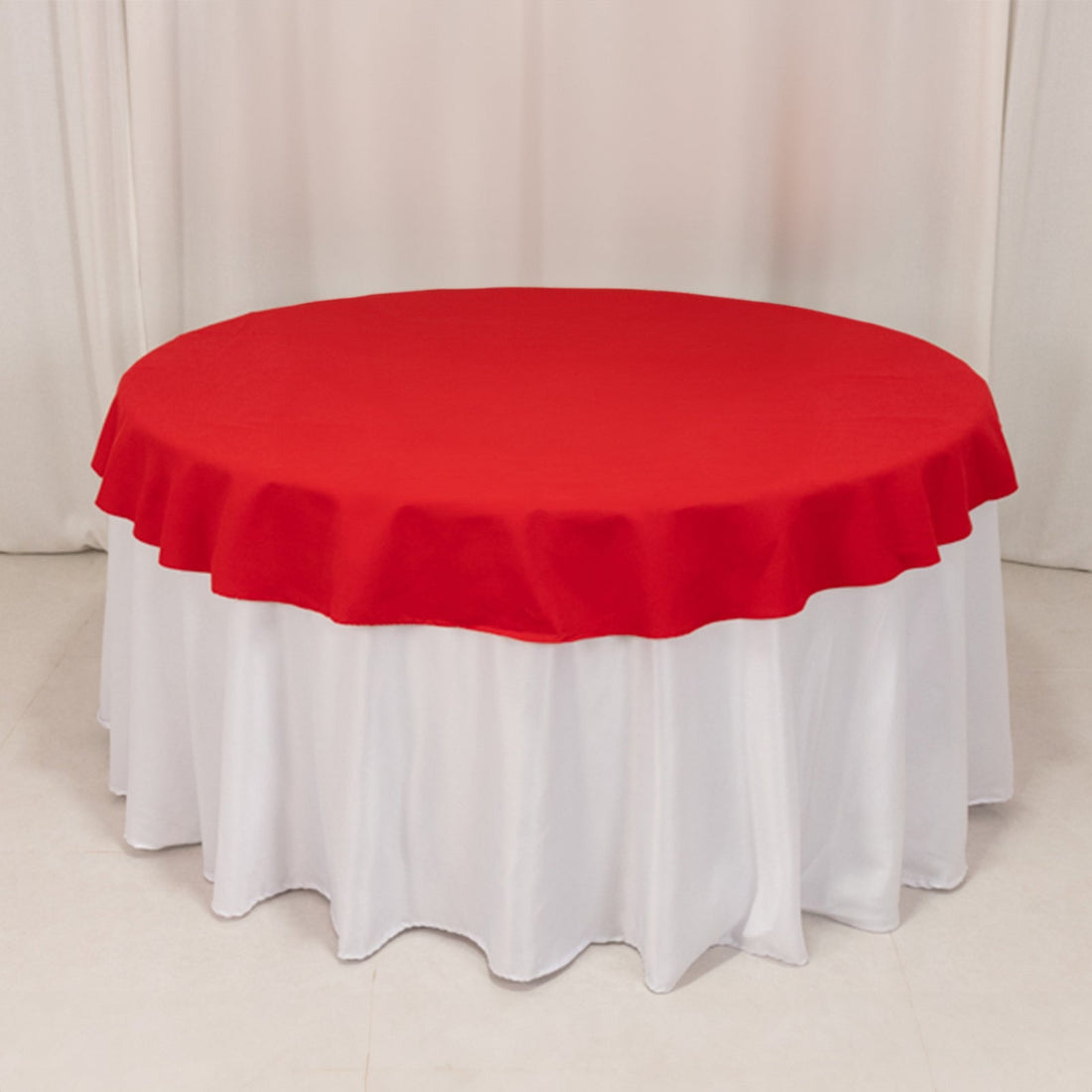 Red round tablecloth draped over a white table.