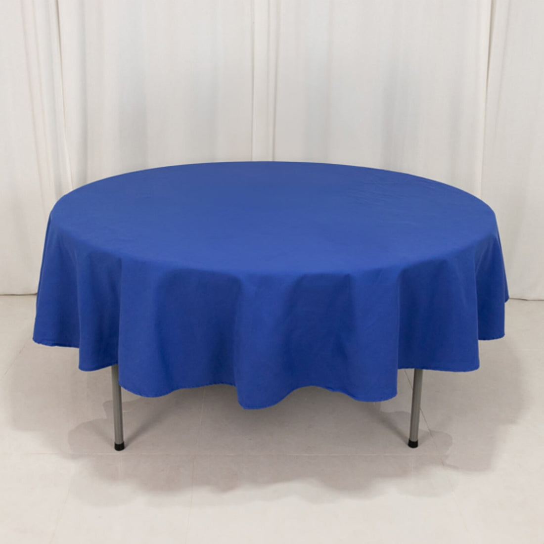 Round blue tablecloth on a table with a plain backdrop.