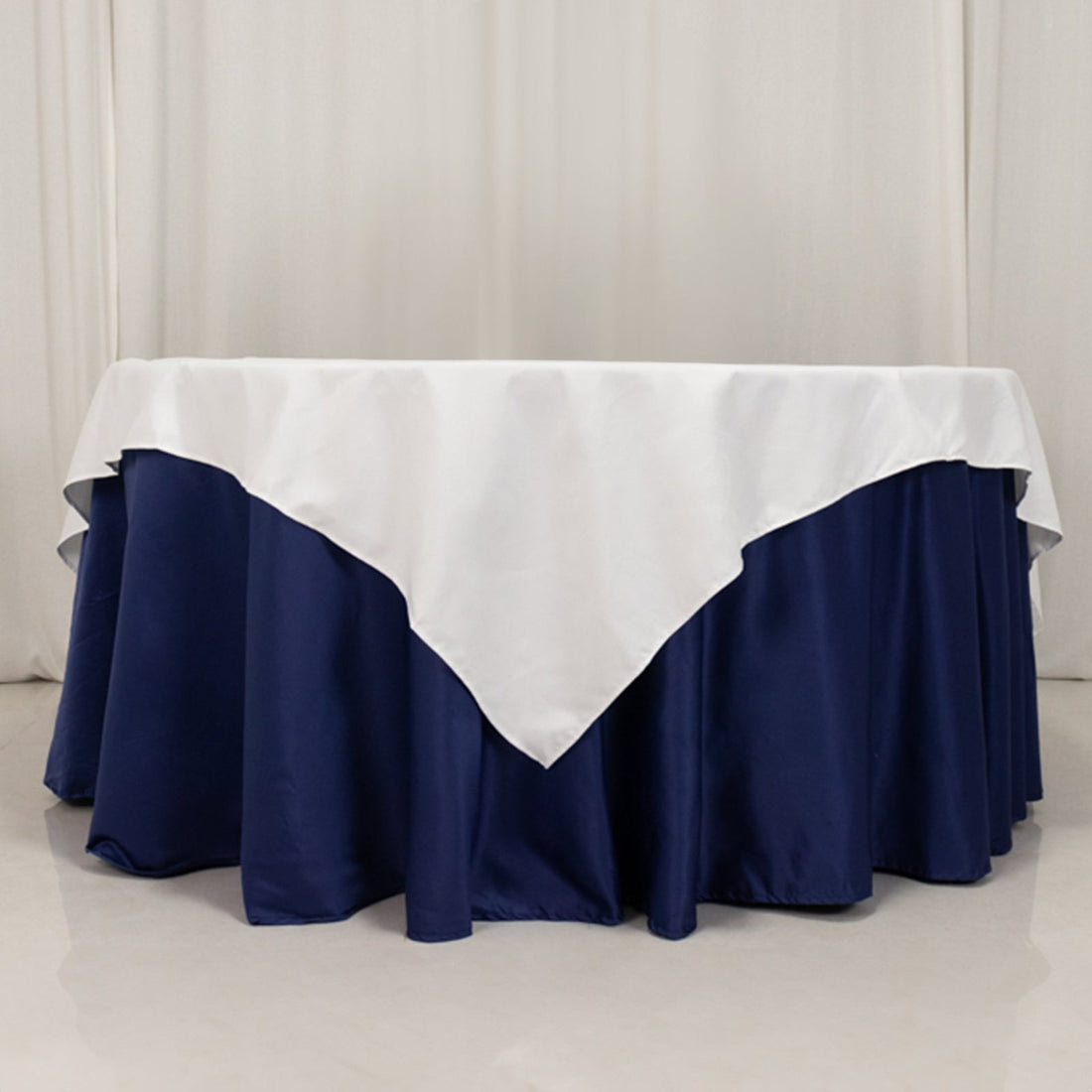 Navy blue tablecloth with white overlay, elegantly draped on a round table.