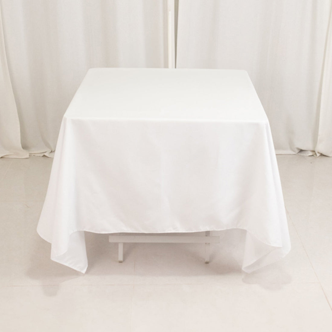 White tablecloth draped over a square table in a studio setting.