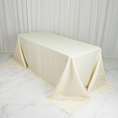 Cream embroidered tablecloth draped over a rectangular table in a white studio