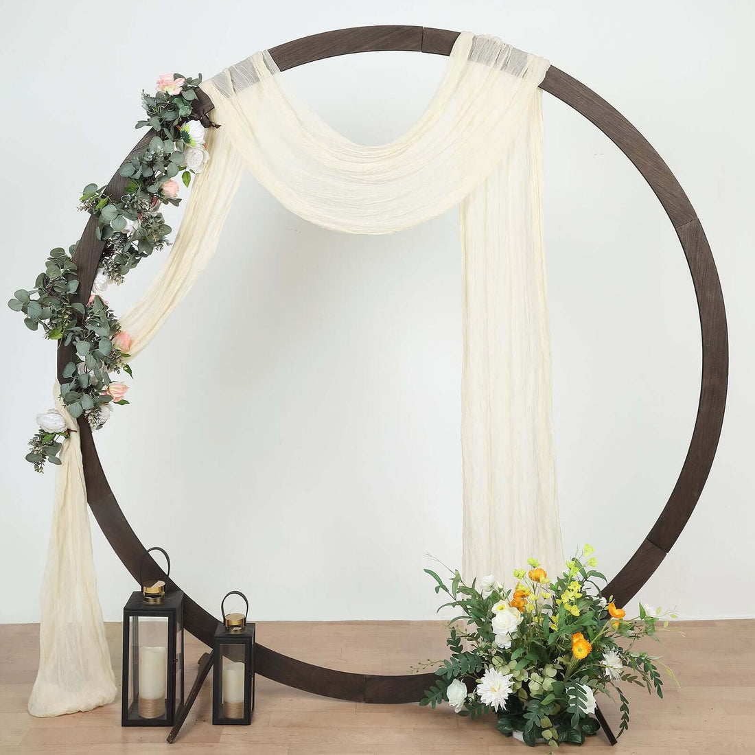 Decorative circular backdrop with flowers, drapes, and lanterns for events or photoshoots.