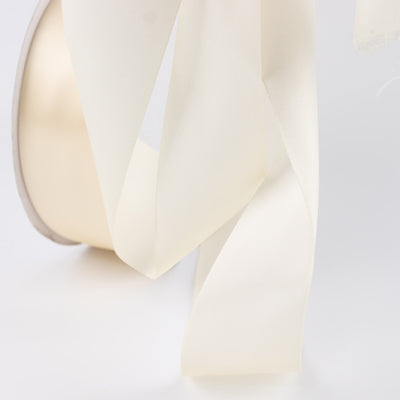 Cream satin ribbon detail on white fabric close-up