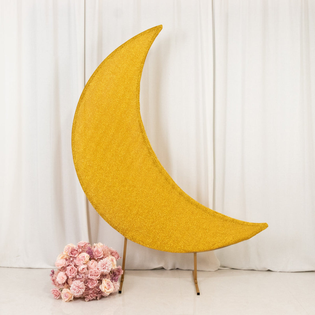Gold glitter crescent moon decoration with pink roses in the foreground.