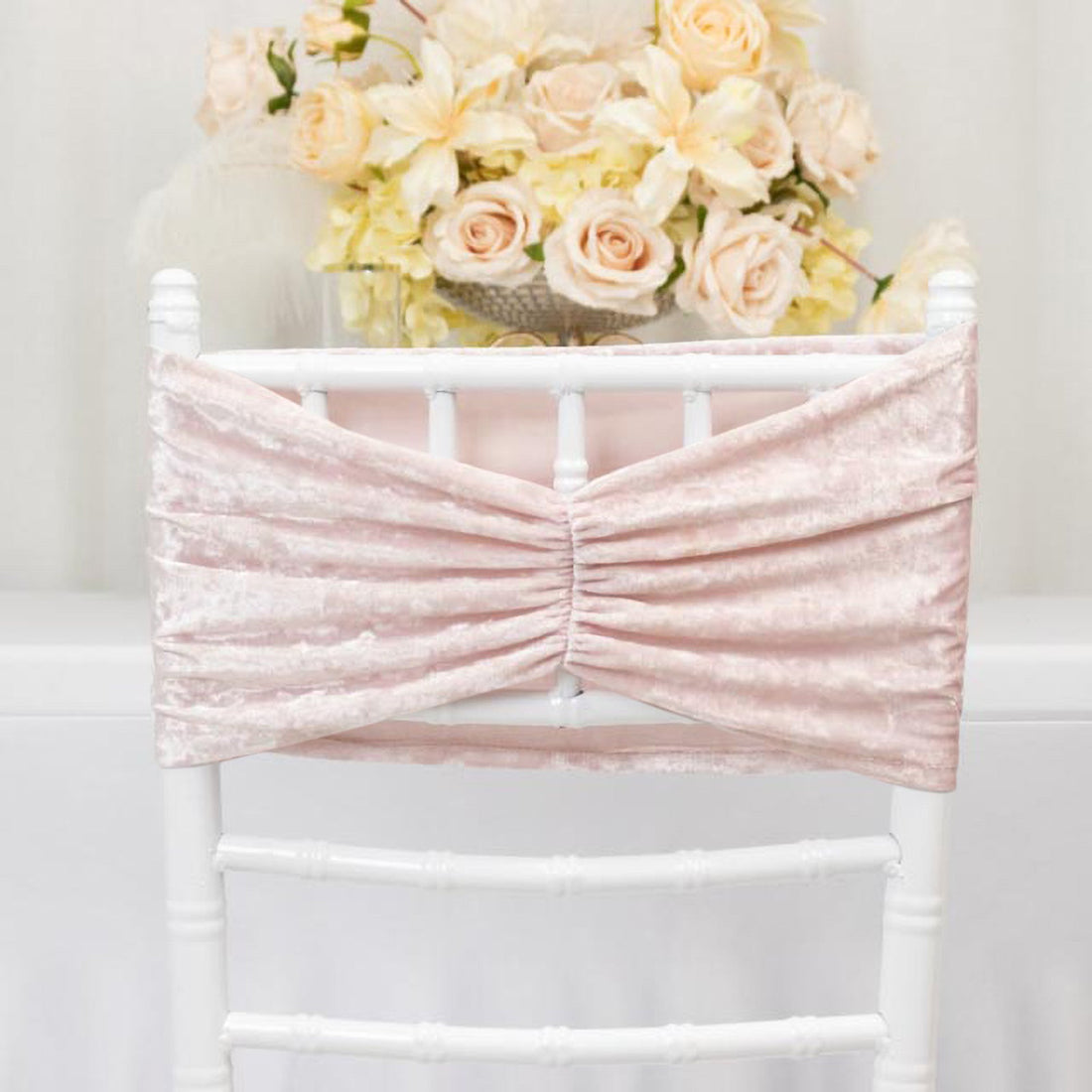 Pink velvet chair back cover with ruched design against soft floral backdrop.