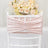 Pink velvet chair back cover with ruched design against soft floral backdrop.