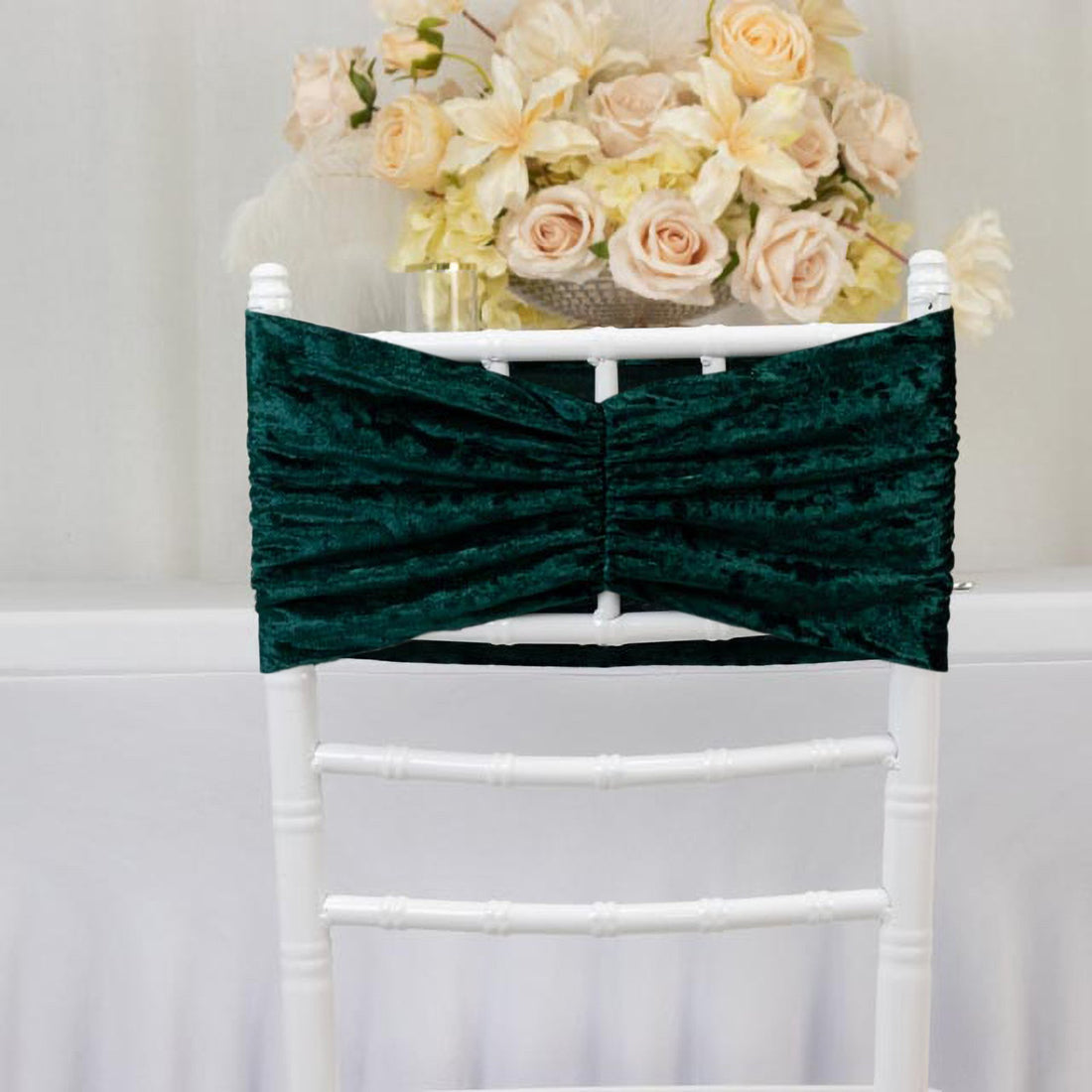 Emerald green chair cover with ruching design against a plain background.