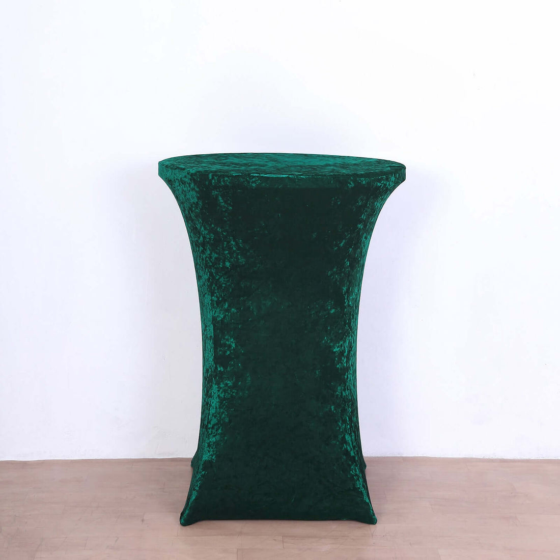 Green velvet table cover on a round table against a white background.