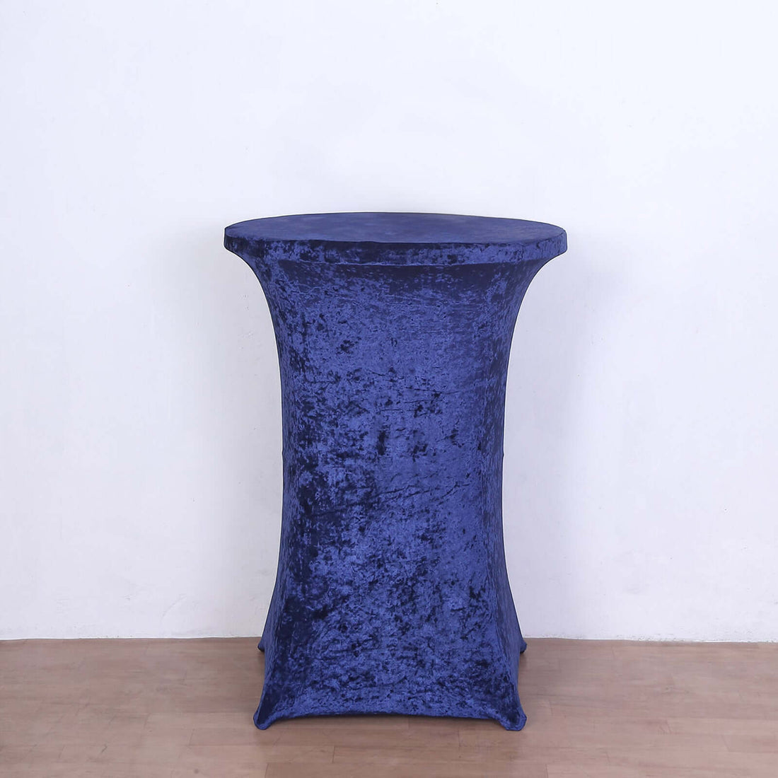 Round blue velvet table cover on a plain backdrop.