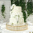 Elegant three-tier wedding cake adorned with white roses on a decorated table.