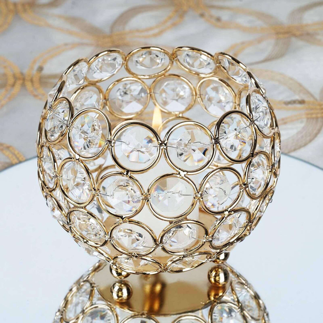 Gold crystal candle holder with decorative design and reflective base.