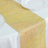 Gold sequined table runner on a white tablecloth with decorative plates.