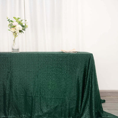 Green sequin tablecloth draped elegantly on a table with a floral arrangement.