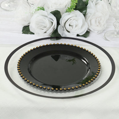 Black decorative plate with gold beading on a table setting.