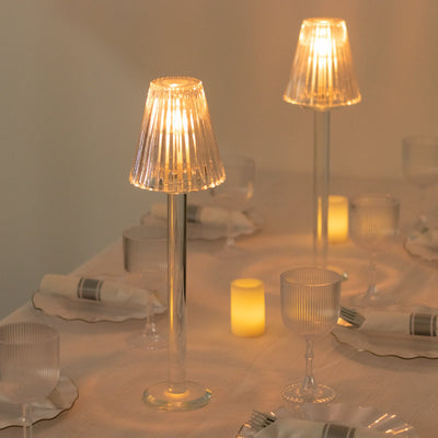 Elegant glass table lamps illuminating a dining setup with candles and glassware.