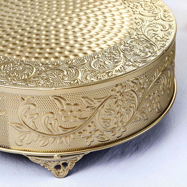 Gold ornate cake stand with textured surface and floral engravings.
