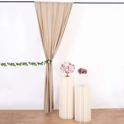 Decorative flowers on pedestals with draped curtain backdrop.
